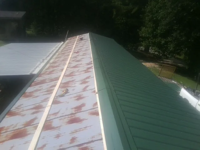 Old rusted panels beside newly installed green metal roofing — Wind Damage Roof Repair by Roofing Brothers in Hightstown