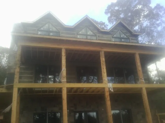 Dormers and porch framing on a large log home under construction — Roof Coating work by our crew in Hightstown