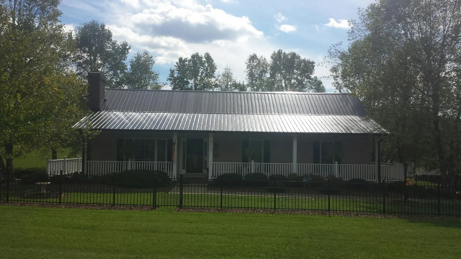 Gray metal roof on a brick ranch with a full width front porch — Gutter Guard Installation work by our crew in Hightstown