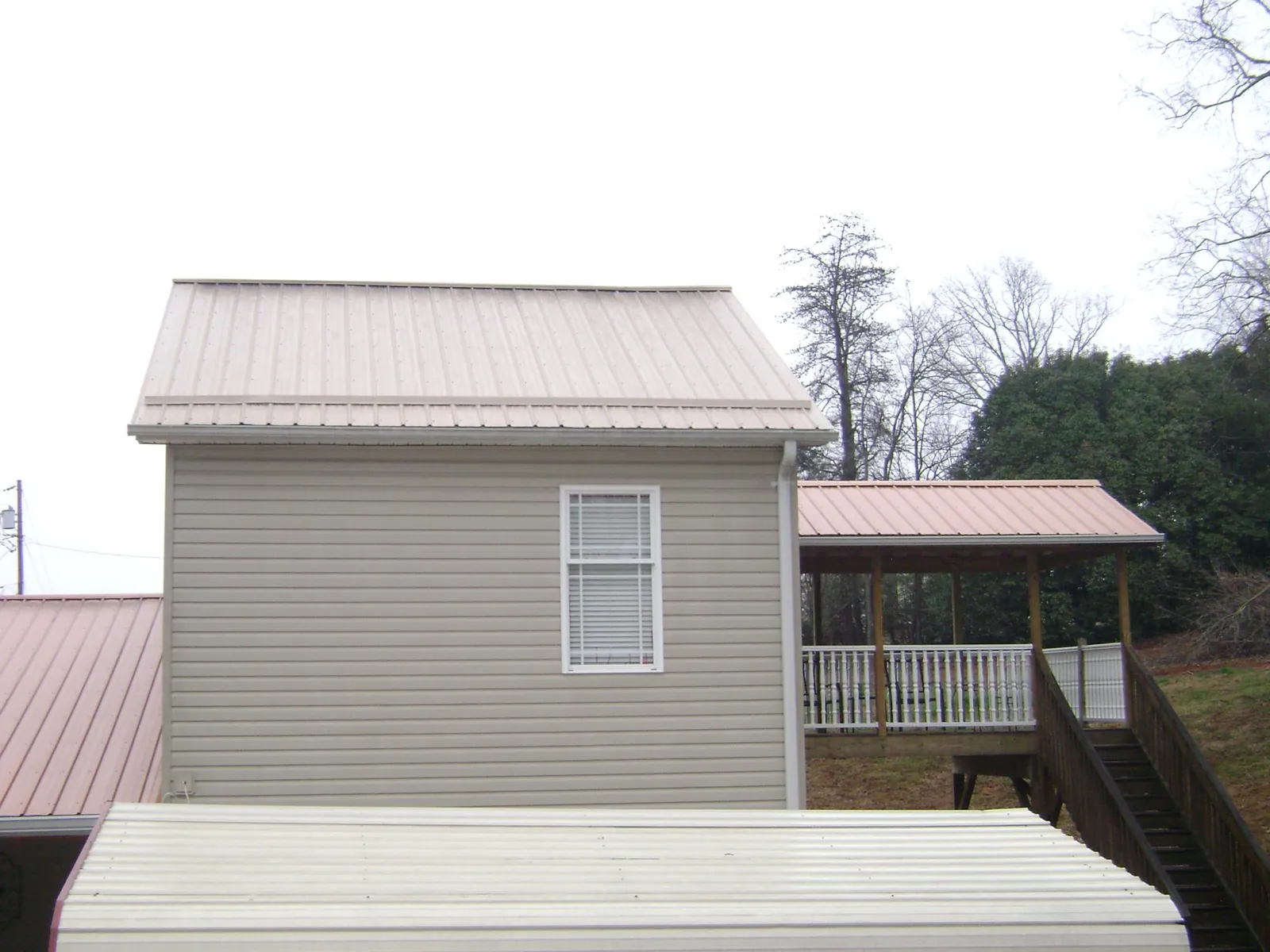 Tan metal roofs on a two story addition and attached porch, from a Roof Replacement job in Hightstown