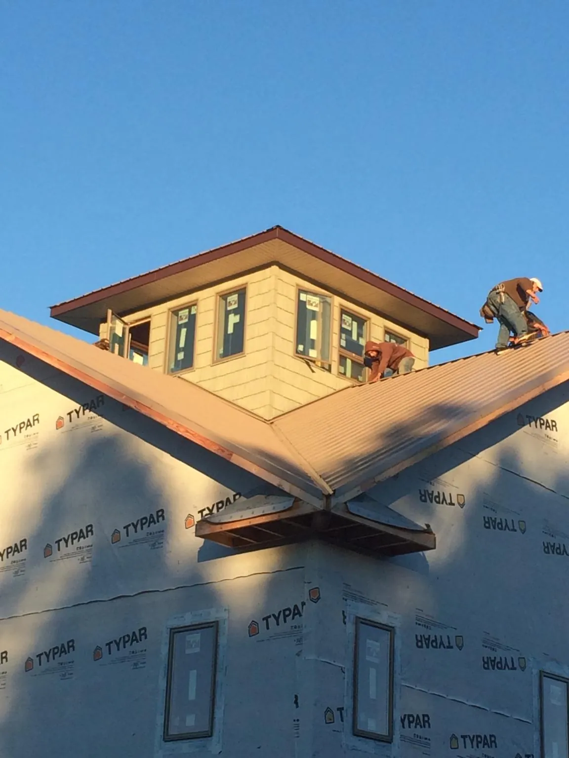 Roofers working around a rooftop cupola on a new metal roof at sunset — Roof Waterproofing in Hightstown by Roofing Brothers